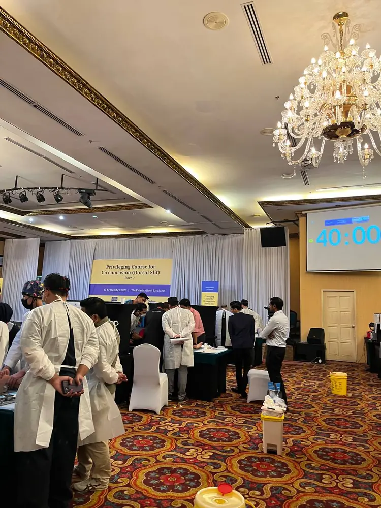 Dewan majlis The Katerina Hotel semasa penilaian berstesen PCC2-1 — peserta berbaju pelindung menunggu giliran, sepanduk kursus dan pemasa 40 minit pada skrin