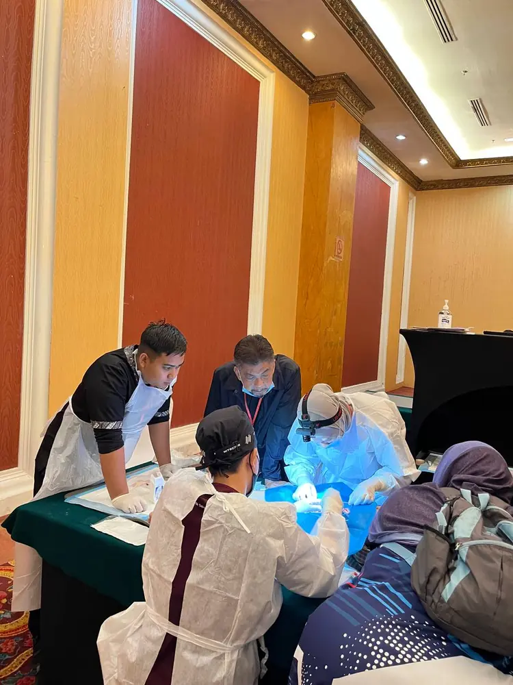Petugas dan fasilitator bermask bekerja di stesen prosedur yang bertutup sepenuhnya dengan kain biru semasa sesi penilaian PCC2-1 di The Katerina Hotel