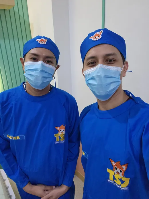 Two clinic staff in blue scrubs bearing the TSJ Tekno Sunat Junior logo before the training session