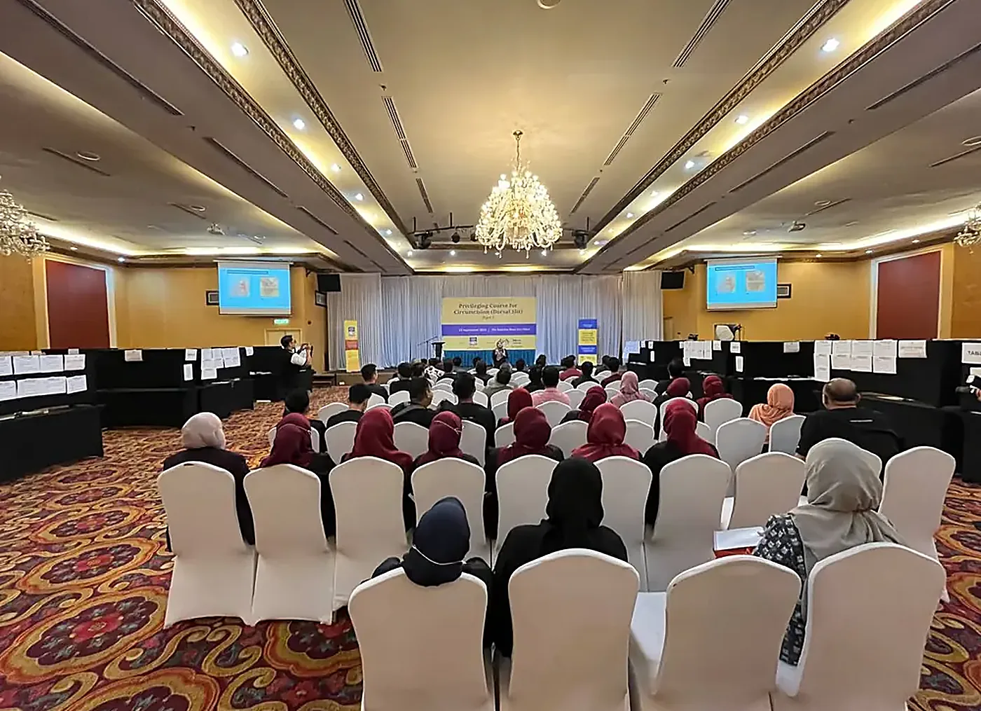 Dewan kursus PCC2-1 dan CCC7 di The Katerina Hotel, Batu Pahat penuh dengan peserta, dengan sepanduk kursus dan sepanduk MADOCS di pentas
